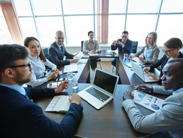 A group of litigation team members around a conference table, reviewing digital case files on laptops.